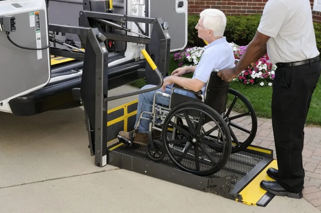 Caregiver assisting elderly man in wheelchair onto a van's accessibility lift.
